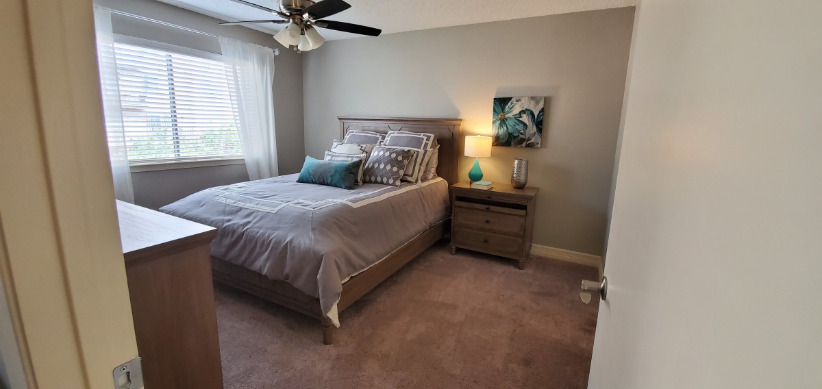 A cozy bedroom with a neatly made bed, nightstand, and soft lighting.