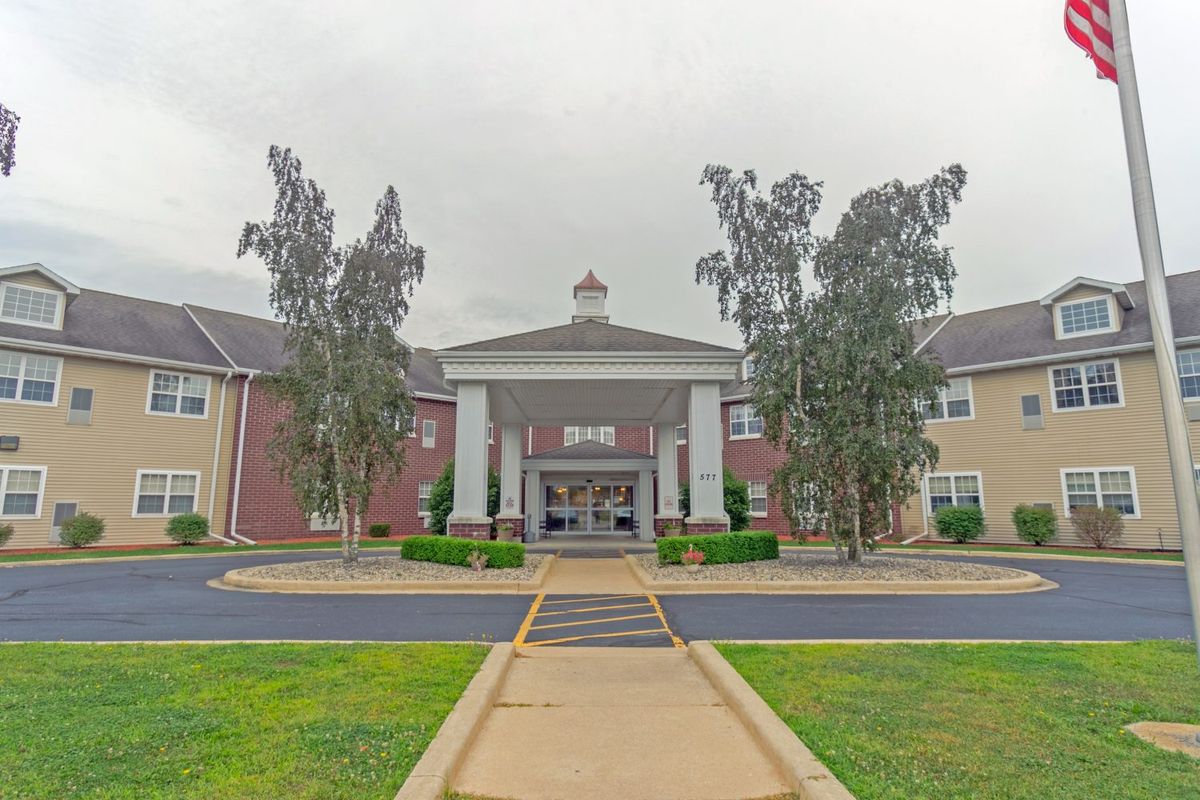 An exterior view of a building entrance with trees and a walkway.