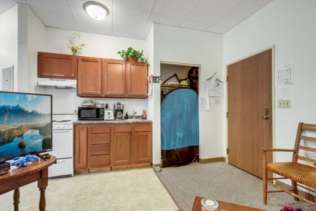 A cozy kitchen area with wooden cabinets, various appliances, and a decorative plant on display.