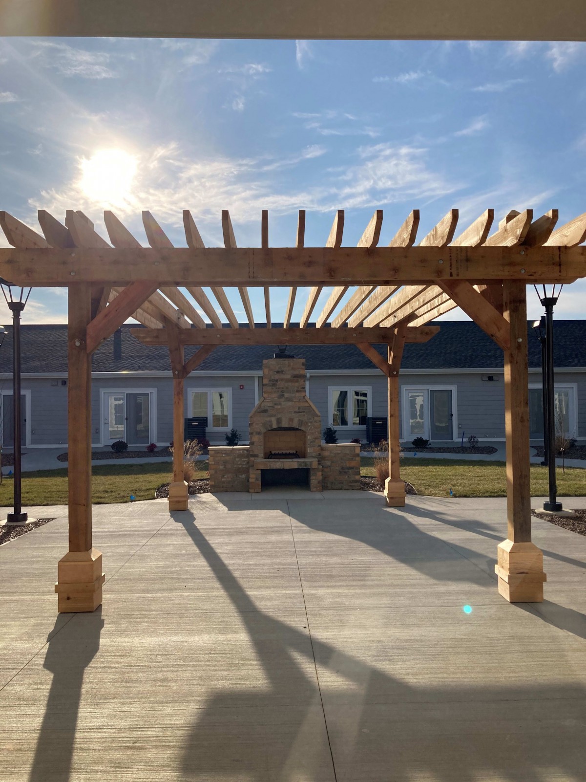 A sunlit wooden pergola in an outdoor courtyard setting.