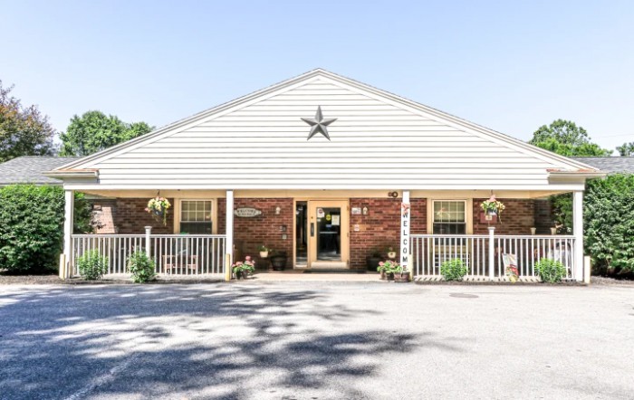 A small, single-story brick building with a star decoration above the entrance and a white railing on the porch.