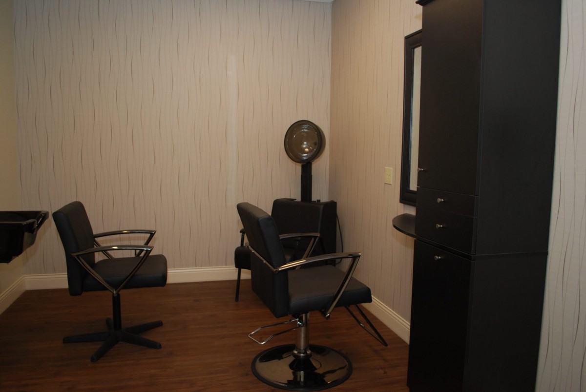 A modern hair salon interior with chairs, a mirror, and a hair dryer.
