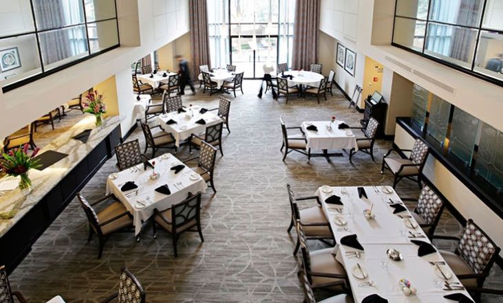 An elegantly set dining room with white tablecloths and neatly arranged chairs in a spacious restaurant.