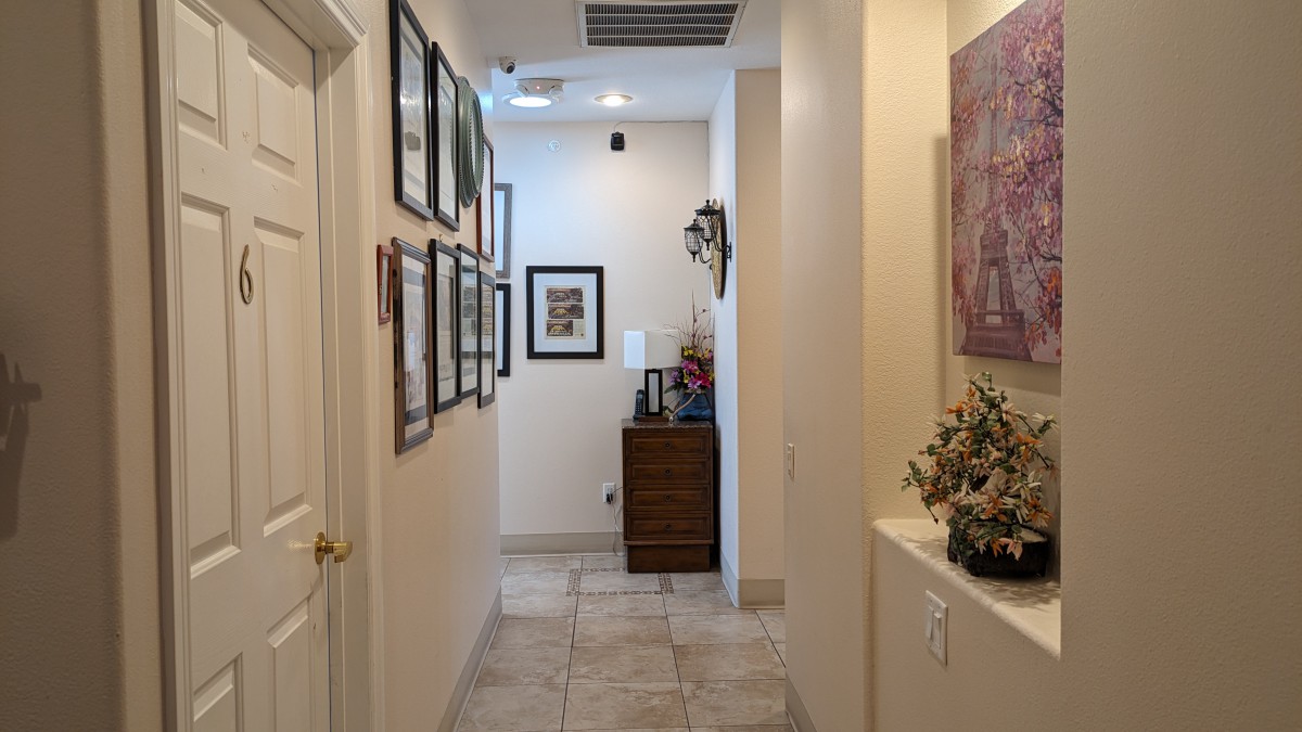 A well-decorated hallway featuring framed pictures and a small cabinet with decorative items.