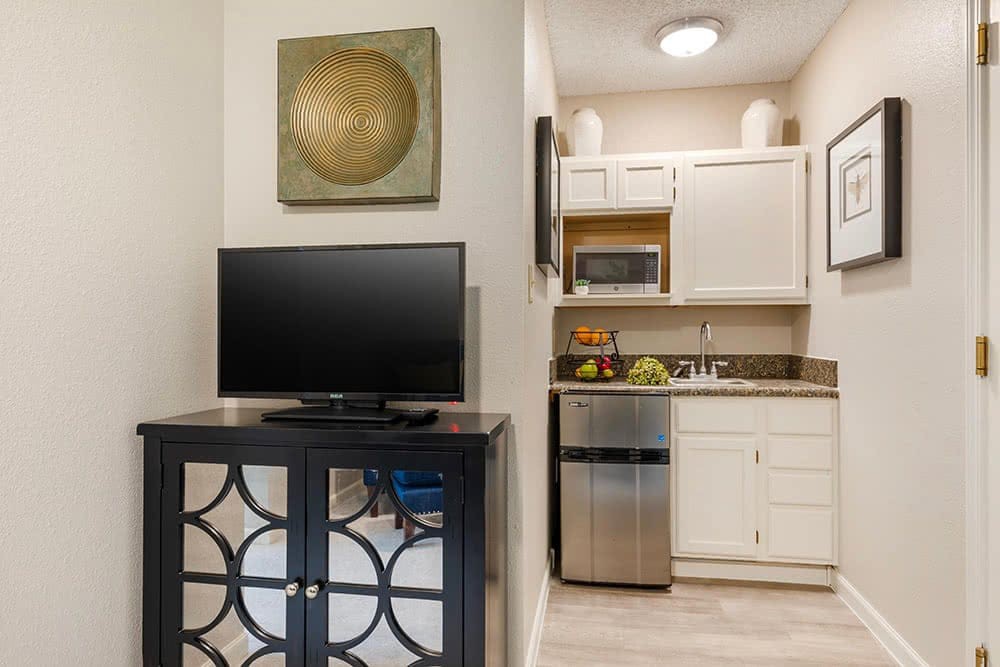 A cozy apartment kitchen with a TV and modern cabinetry.