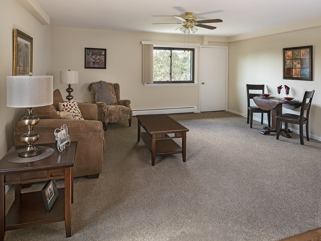 A spacious living room with comfortable seating, a coffee table, and a dining area in the background.