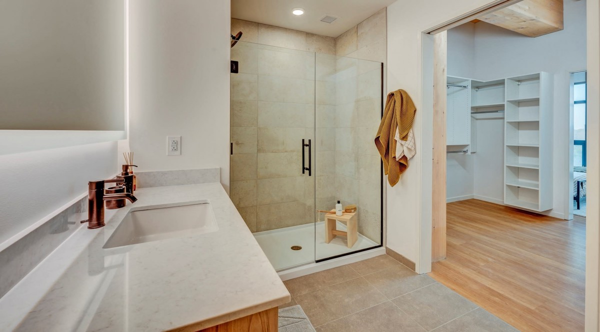 A modern bathroom with a glass-enclosed shower and a neatly organized vanity area.