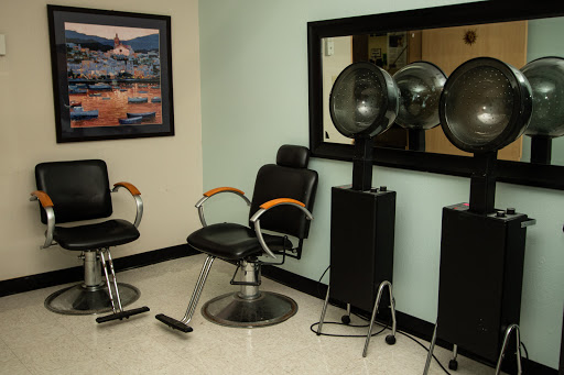 A glimpse into a contemporary beauty salon featuring barber chairs, hair dryers, and a large mirror.