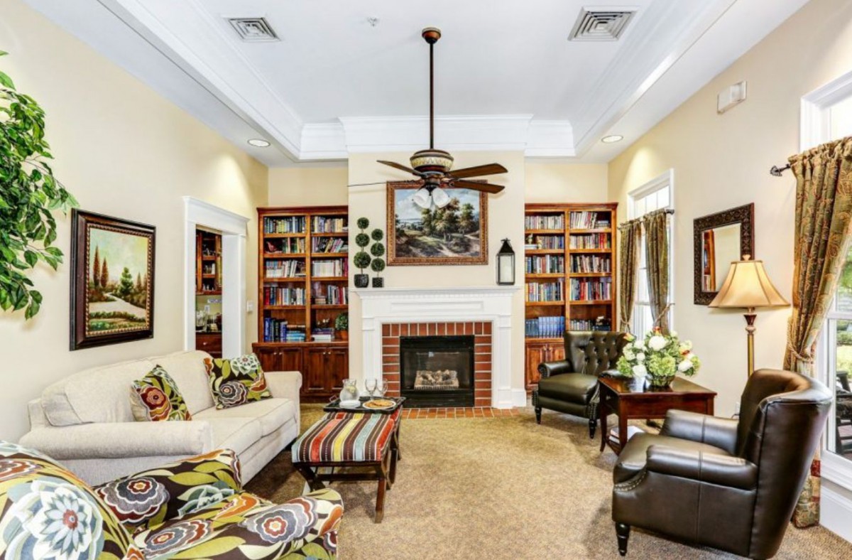A cozy living room with bookshelves flanking a central fireplace, featuring comfortable seating and a ceiling fan.