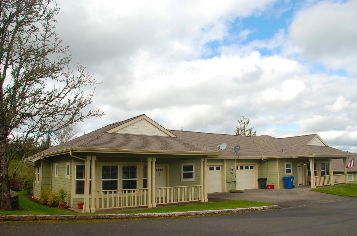 A single-story suburban house with a garage and cloudy sky overhead.