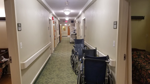 A quiet hallway in a healthcare facility with wheelchairs positioned along the side.