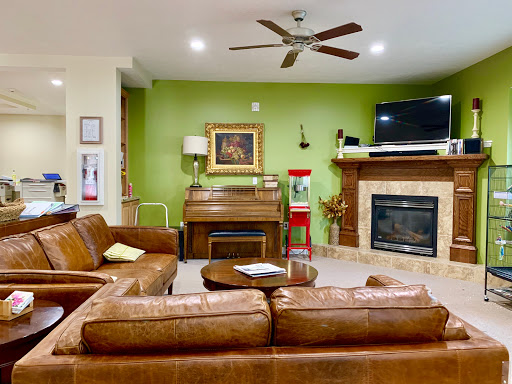 A cozy living room featuring a leather sofa, piano, and a warm green wall.