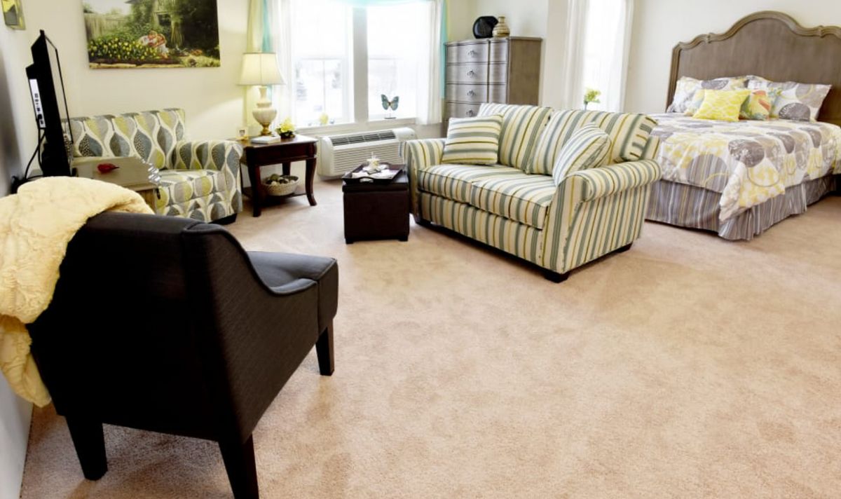 A cozy living room with a striped sofa, armchair, and coffee table on a carpeted floor.