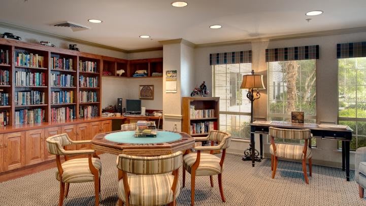 A cozy reading and study area with bookshelves, a round table, and comfortable chairs.