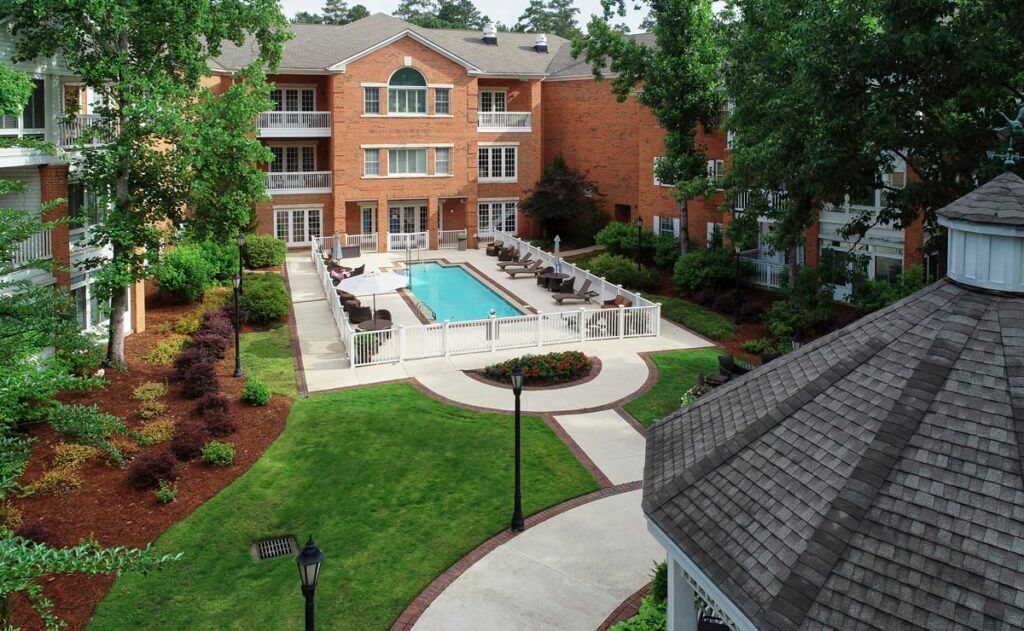 Aerial view of a residential apartment complex with a swimming pool surrounded by landscaped greenery.