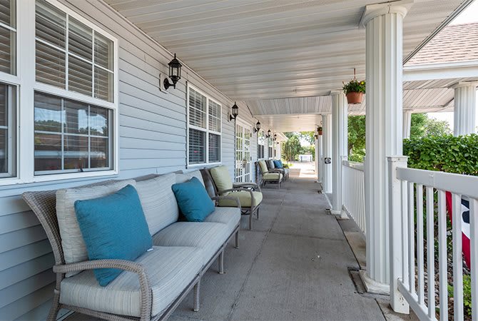 A cozy porch with comfortable seating and decorative pillows under a covered patio.
