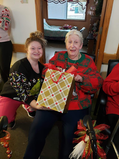 Two women celebrating the holiday season together, sharing a joyful moment with a gift.