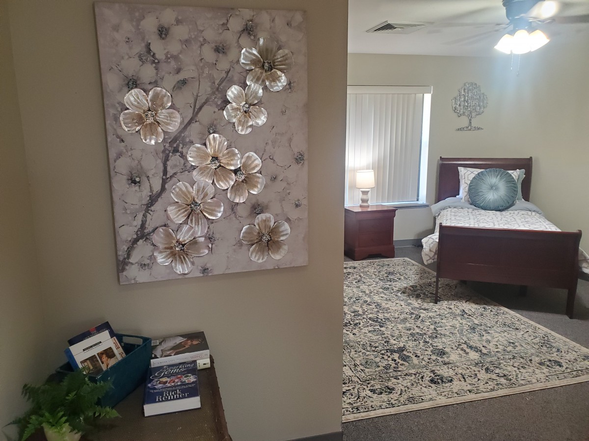 A cozy bedroom with floral artwork and a well-arranged interior.