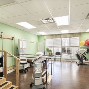 A well-equipped physical therapy room with exercise machines and rehabilitation equipment.