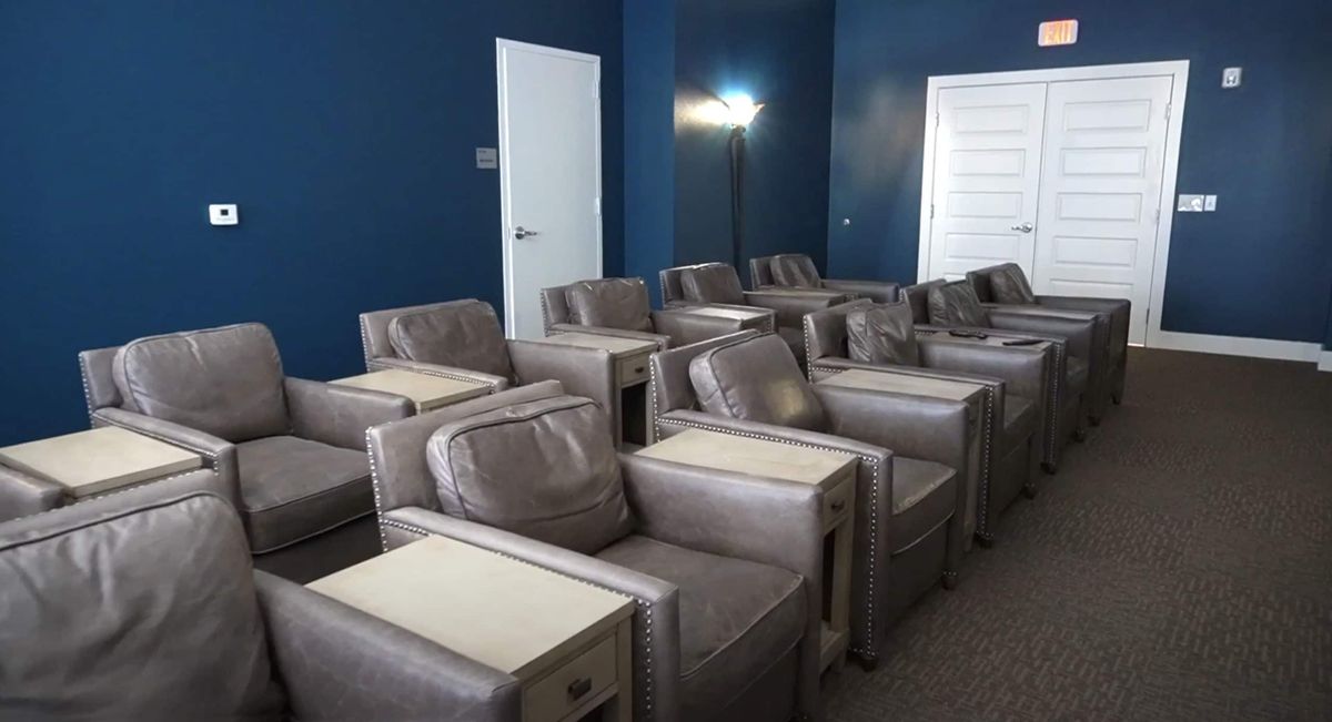 A cozy home theater room with plush leather seating and blue walls.