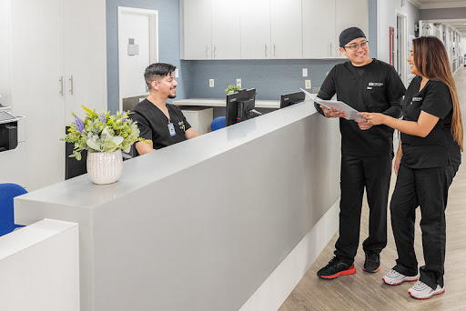 A healthcare professional interacting with the reception staff in a modern medical office.