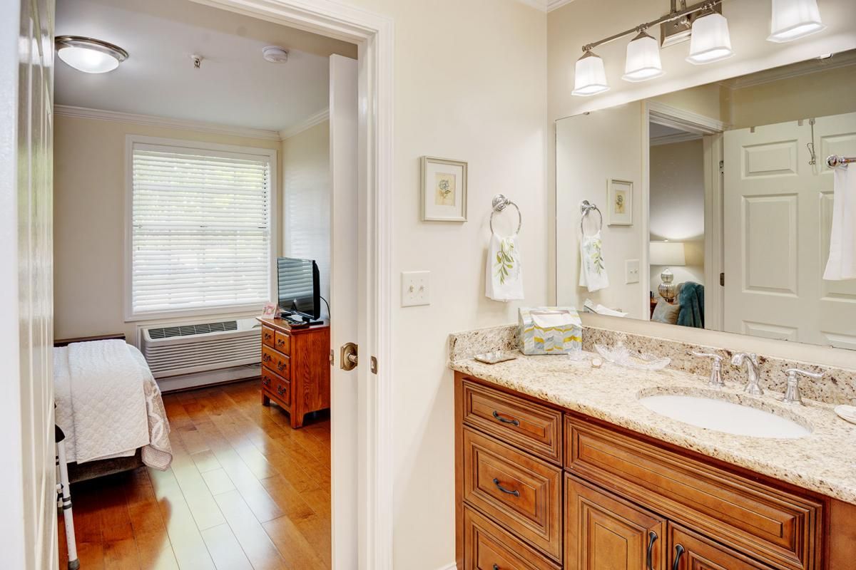 A cozy bedroom connected to a bathroom with wooden cabinetry and a well-lit mirror.