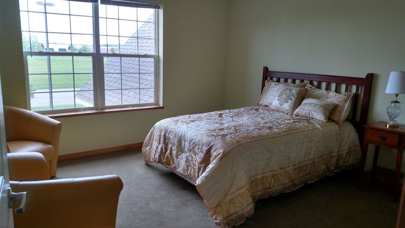 A cozy bedroom with a neatly made bed and large window.
