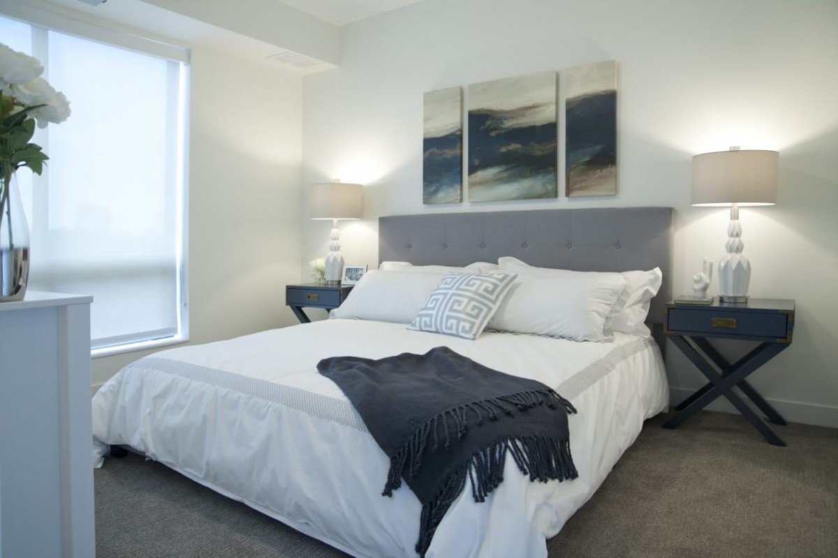 A modern bedroom with a neatly made bed, stylish decor, and soothing artwork on the wall.