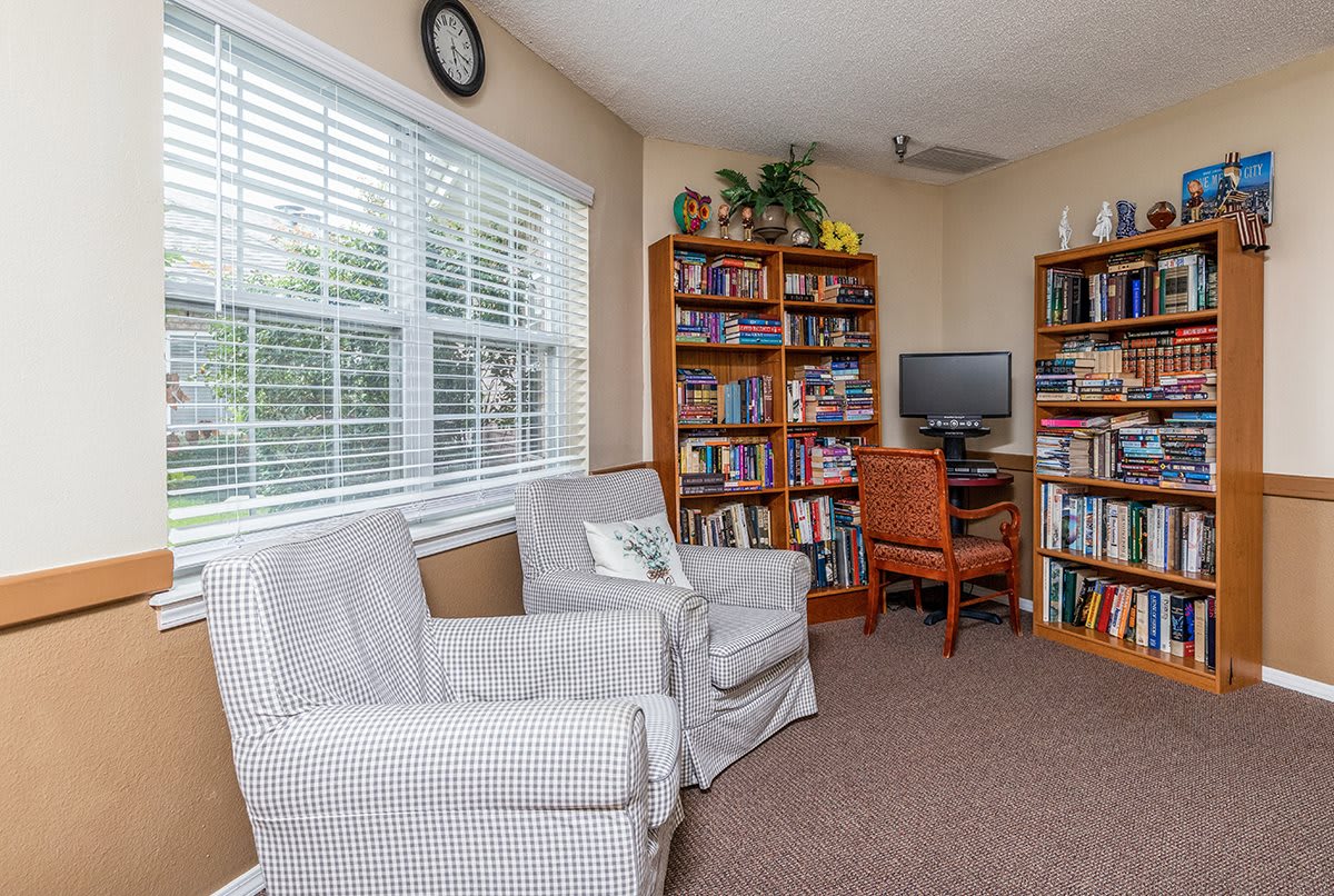 A cozy reading room with armchairs, bookshelves, and a computer desk by the window.