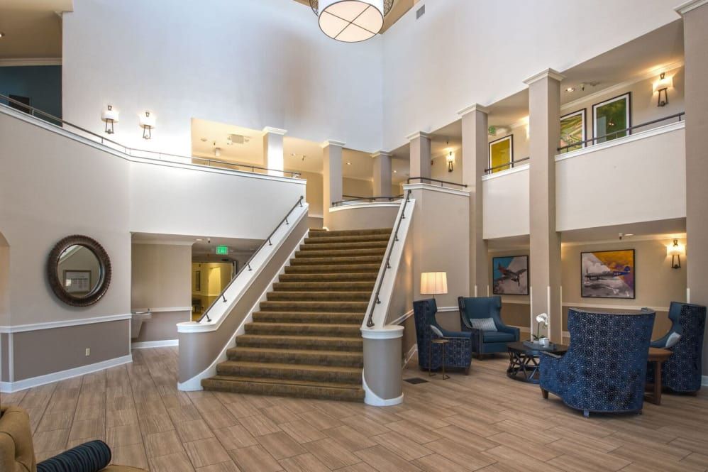A spacious hotel lobby featuring a grand staircase, comfortable seating, and elegant lighting.
