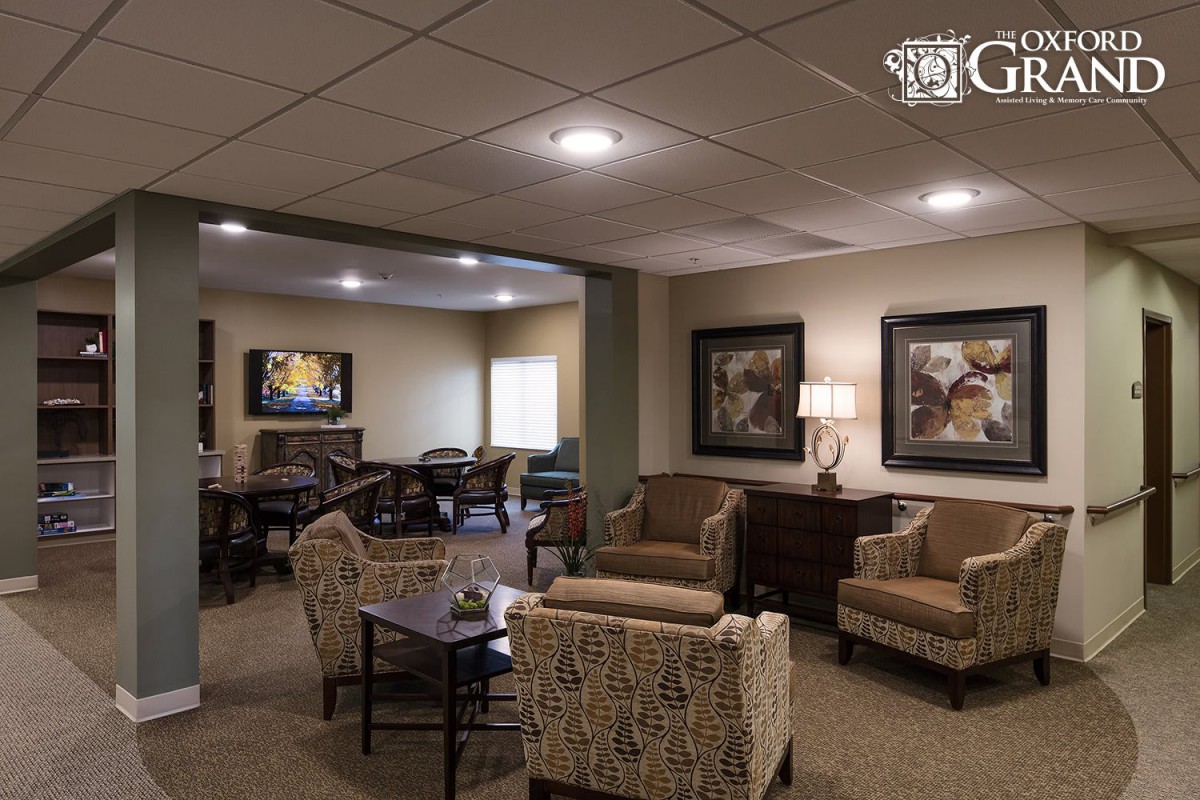 A comfortable and well-furnished lobby with seating arrangements, paintings, and a TV.