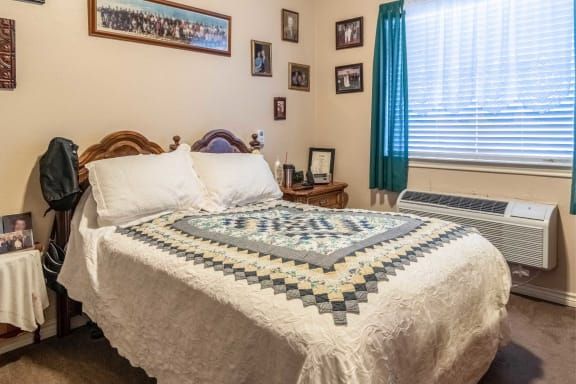 A cozy bedroom with a quilted bedspread and family photographs on the walls.