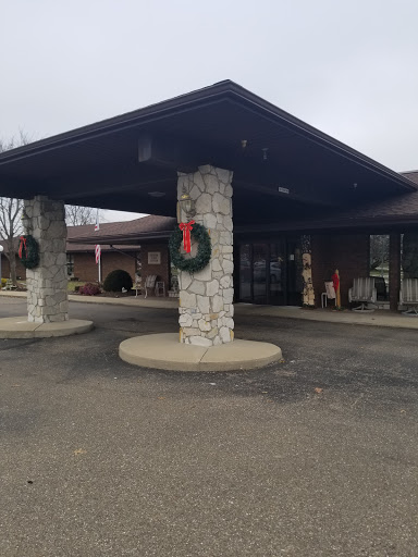 Entrance of a building decorated with holiday wreaths, set against a cloudy backdrop.