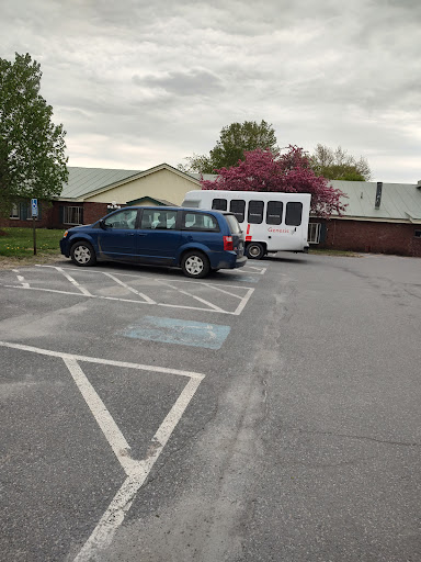 A blue car parked next to a white bus in a quiet parking lot.