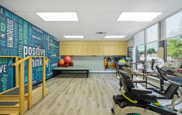 A well-equipped physical therapy room featuring exercise equipment and a motivational wall design.