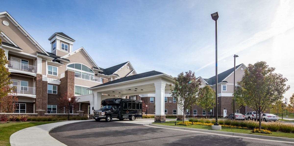 A building with a covered entrance and a vehicle parked on the driveway.