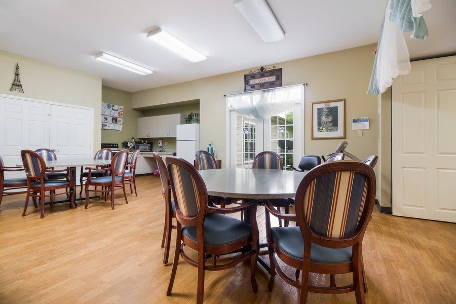 A cozy dining area with multiple tables and chairs, adjacent to a small kitchen space.