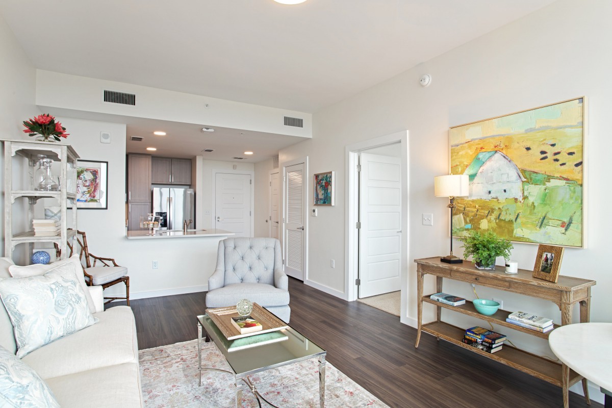 A modern apartment living room with an open kitchen, stylish furniture, and contemporary artwork.