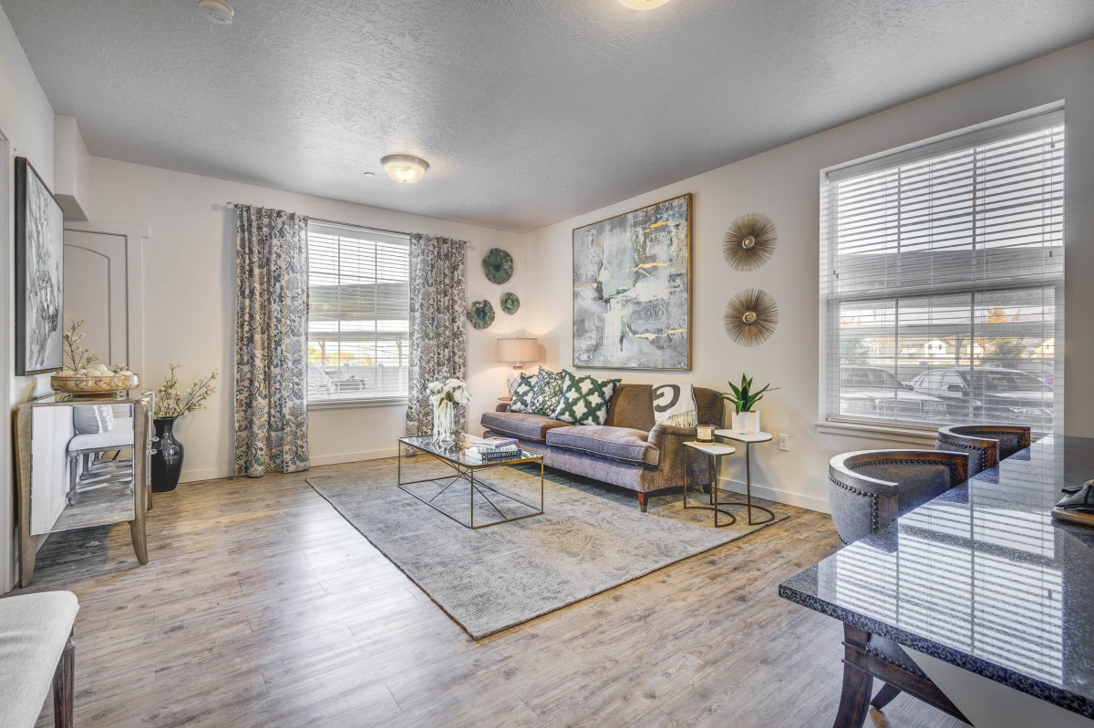 A modern living room with stylish decor and furniture, featuring a comfortable sofa, coffee table, large windows, and contemporary artwork.