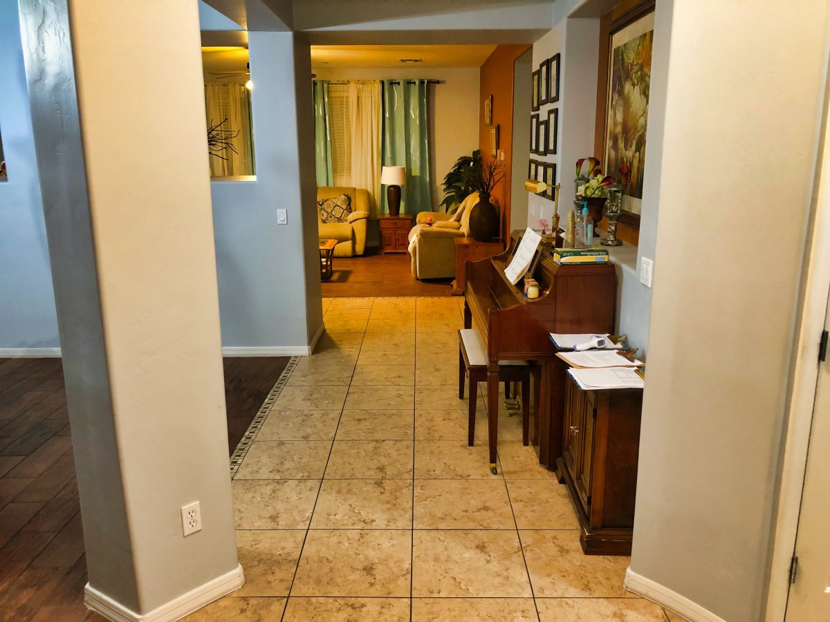 A cozy hallway leading to a warmly decorated living room, with a piano on the side.