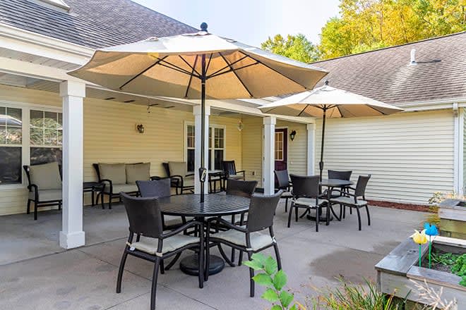 A cozy patio with multiple tables and chairs shaded by large umbrellas, providing a perfect outdoor relaxation spot.
