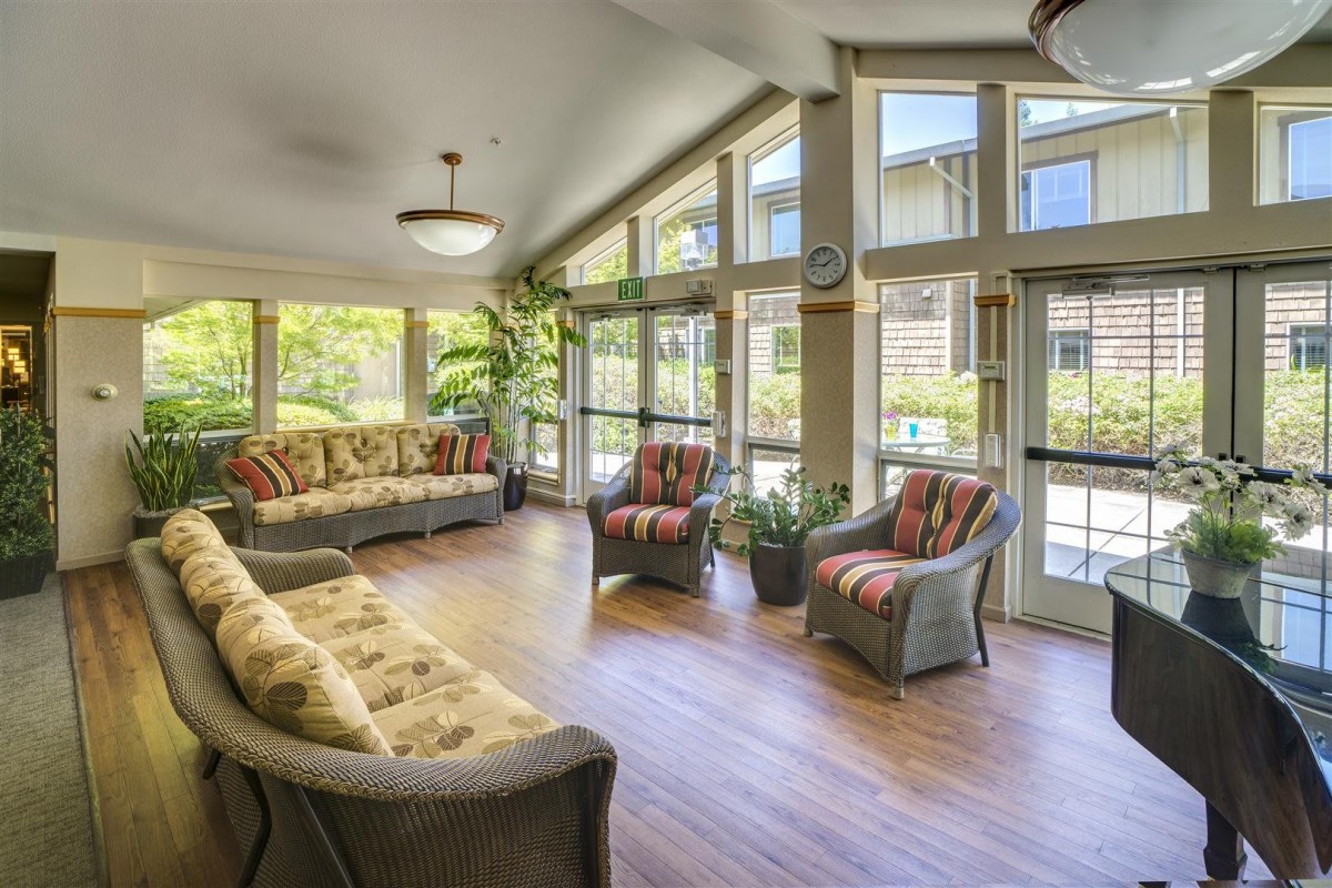 A bright living room with large windows, wooden flooring, and comfortable seating.