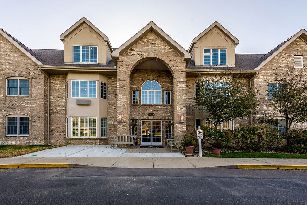 A two-story building with a stone facade and multiple windows, featuring a central entrance.