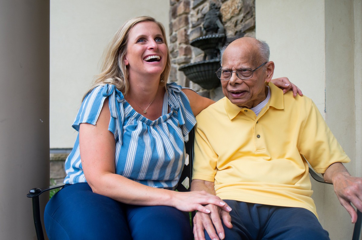 A caregiver and an elderly man share a joyful moment together indoors.