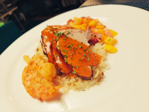 A beautifully plated dish showcasing tender poultry served over rice with vibrant vegetables and a savory sauce.