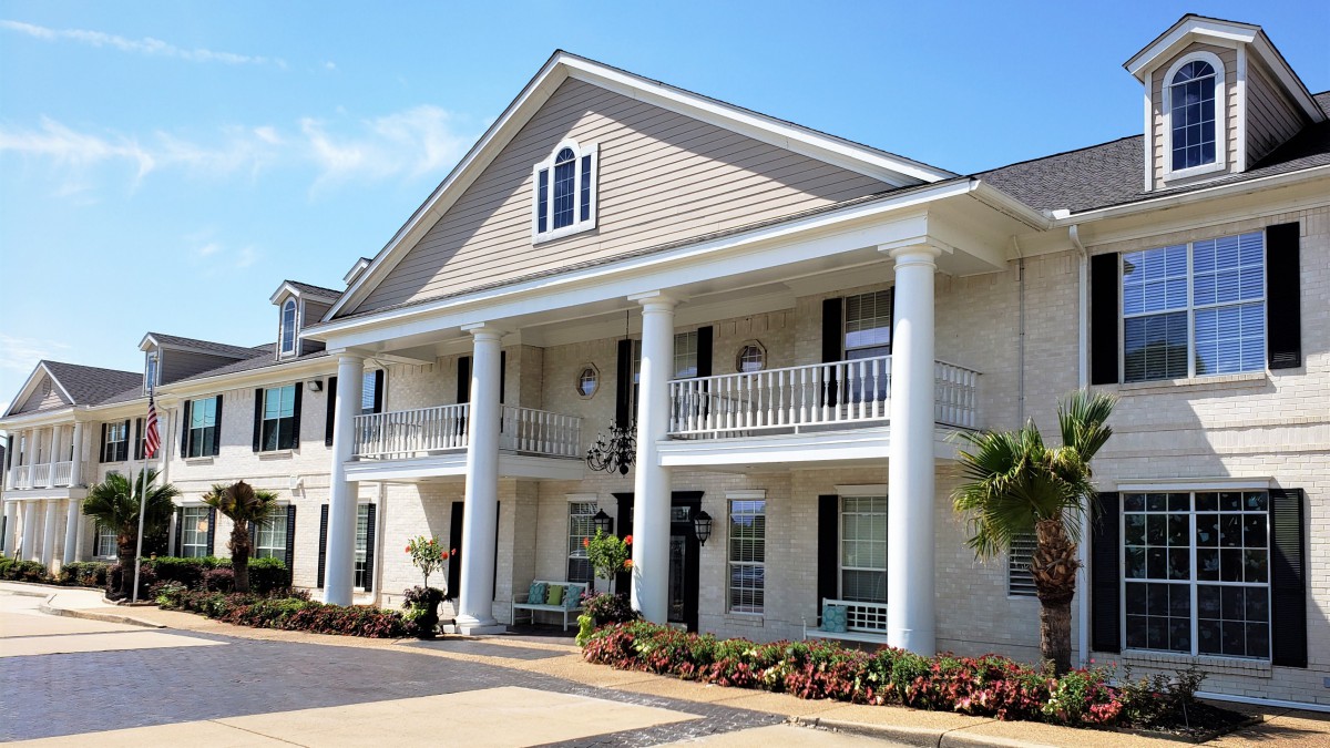 A large residential house featuring classic architecture with prominent columns and a balcony.