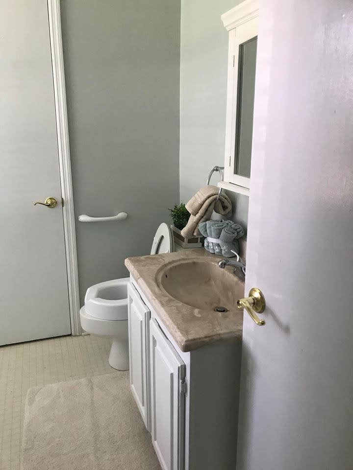 A clean, compact bathroom with a sink, toilet, mirror, and neatly arranged towels.