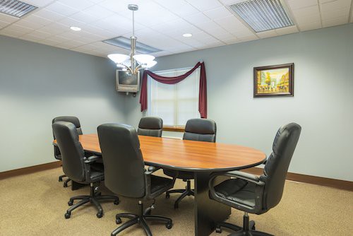 A conference room with a large oval table and several leather chairs.