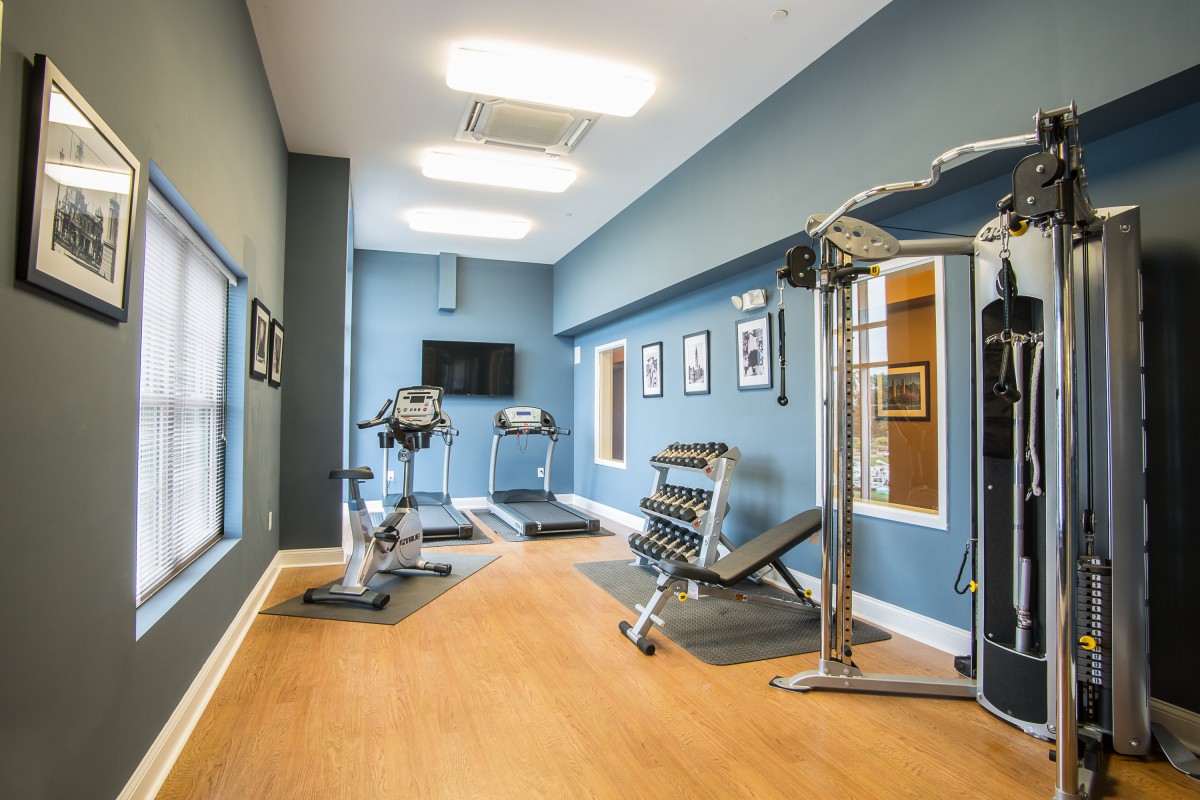 A small gym with various exercise equipment, including treadmills, a stationary bike, and a weight bench.