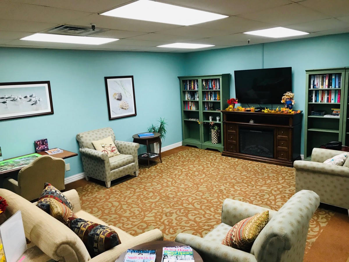 A cozy living room with comfortable seating, a television, and bookshelves.